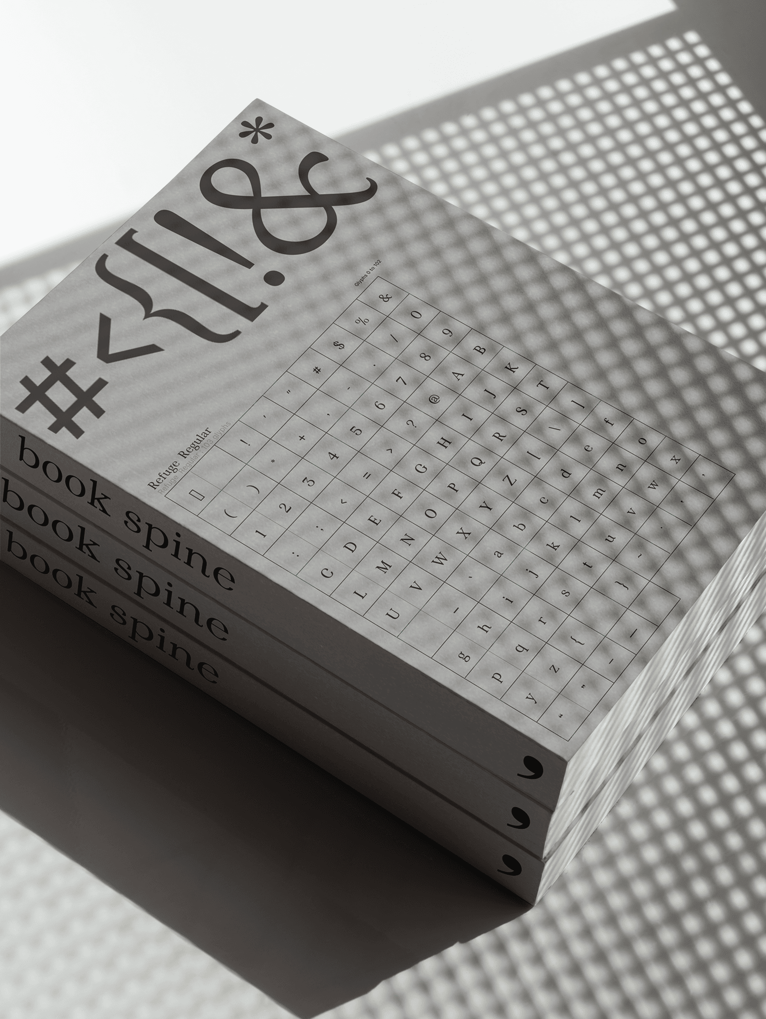 A stack of Refuge type specimen books under dappled light.